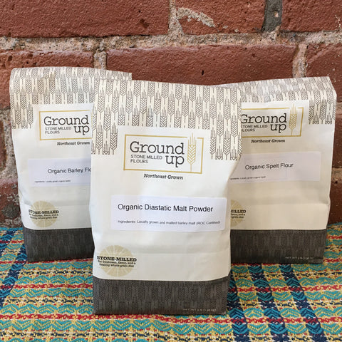 Three bags of Organic Ground Up stone-milled flour: Spelt, Barley, and Diastatic Malted Barley Powder.