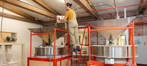 A miller pours grains into the stone mill/